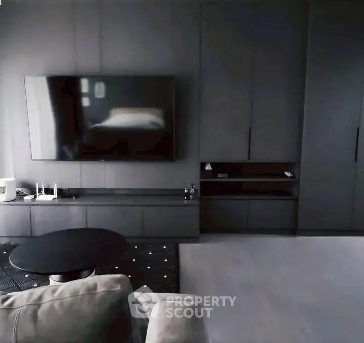 Modern living room with sleek dark furniture and wall-mounted TV