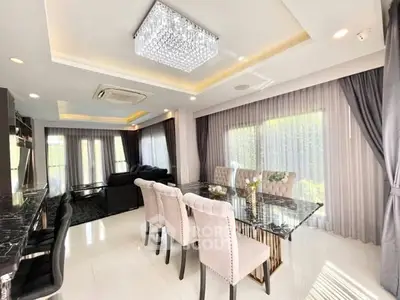 Luxurious open living and dining area with elegant chandelier and plush seating.