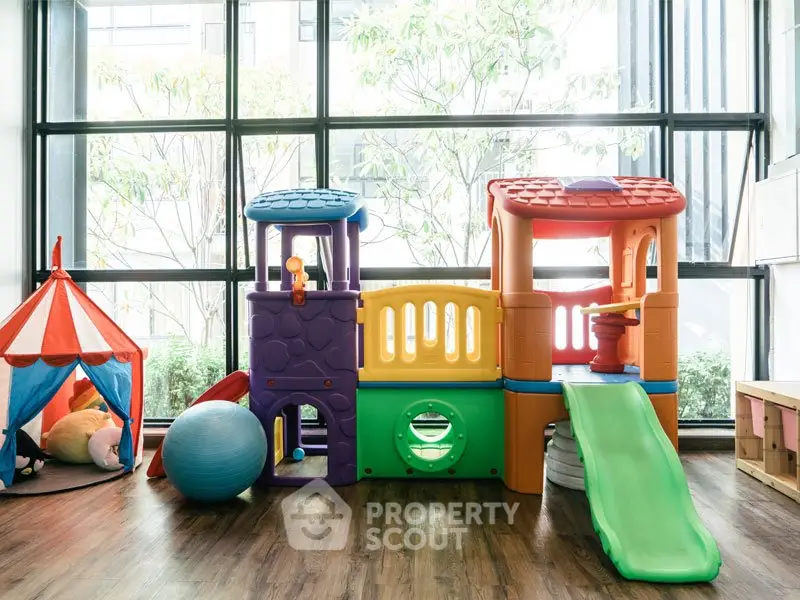 Bright and colorful indoor play area with slide and playhouse, perfect for family-friendly properties.