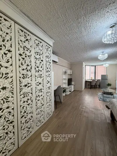 Spacious living room with elegant decor and textured ceiling, featuring modern furniture and wooden flooring.
