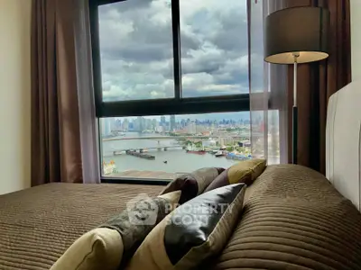 Luxurious bedroom with stunning city and river view from large window.