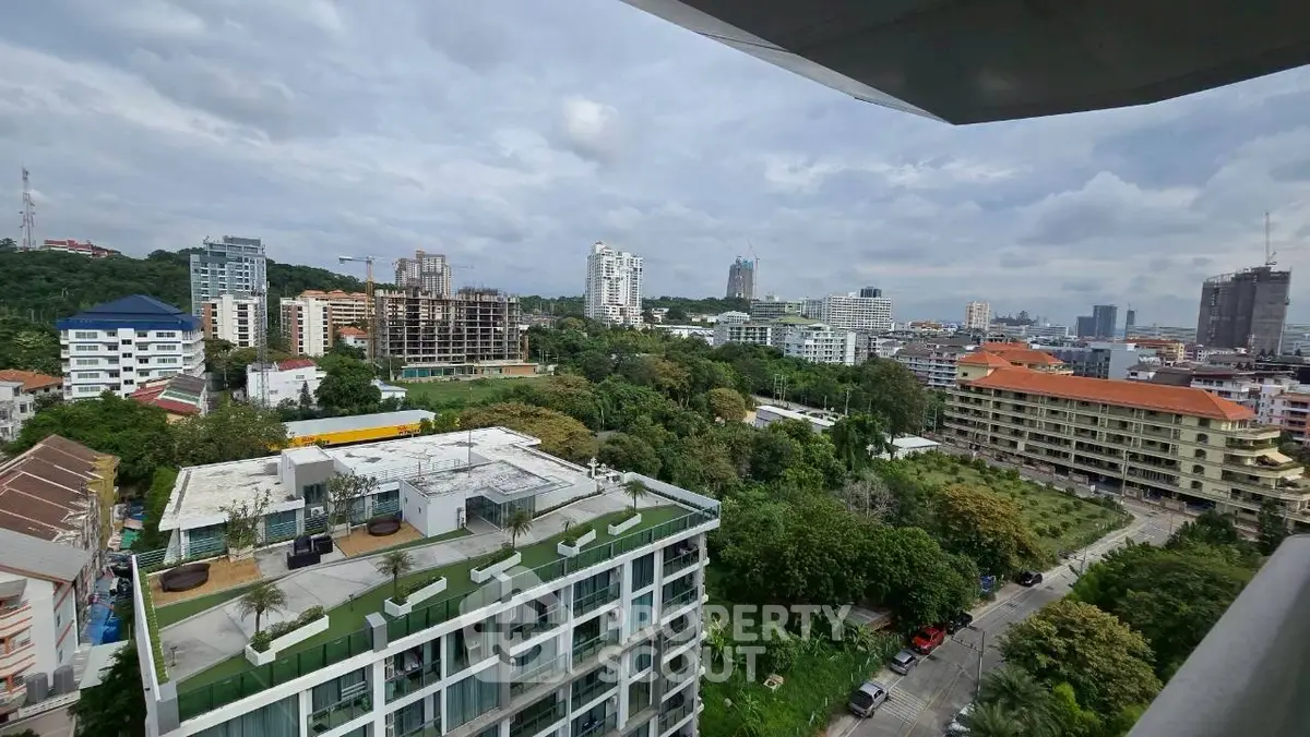Stunning cityscape view from a high-rise balcony overlooking lush greenery and urban skyline.