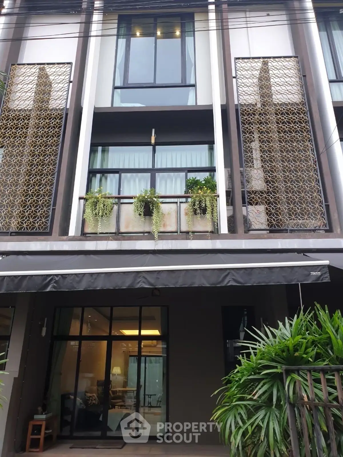 Modern townhouse exterior with stylish balcony and lush greenery