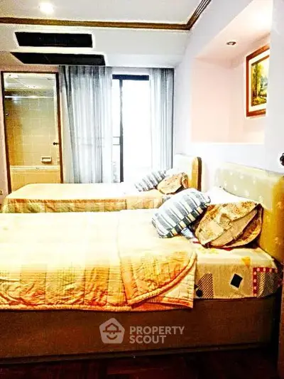 Cozy bedroom with twin beds and large window offering natural light.