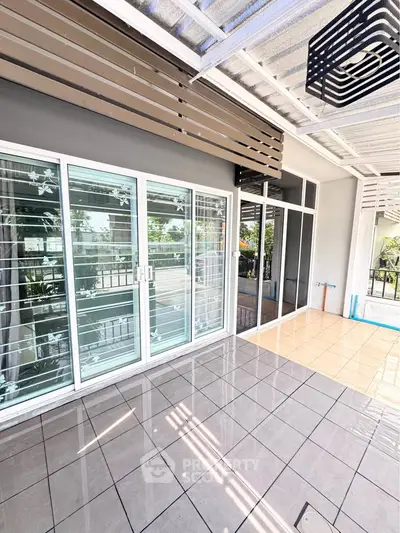 Spacious tiled balcony with sliding glass doors and modern design.
