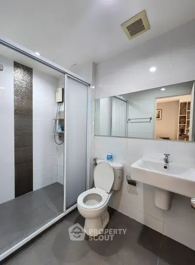 Modern bathroom with sleek design, featuring a glass-enclosed shower and contemporary fixtures.