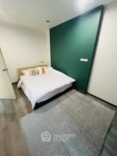 Modern bedroom with stylish green accent wall and cozy bed setup