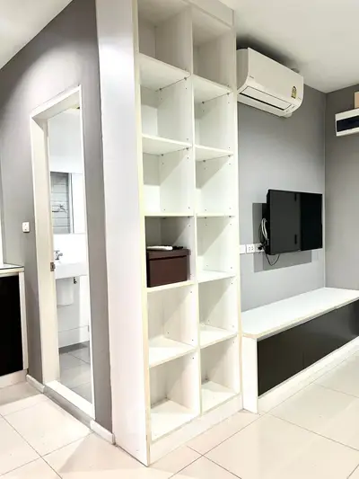 Modern living room with built-in shelving and wall-mounted TV, featuring sleek air conditioning unit.