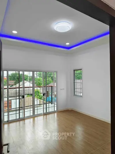 Spacious room with modern lighting and large windows offering a serene view, perfect for a cozy living space.