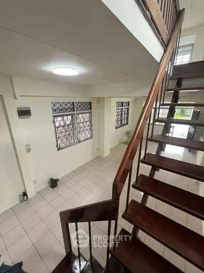 Spacious two-story living area with wooden staircase and tiled flooring