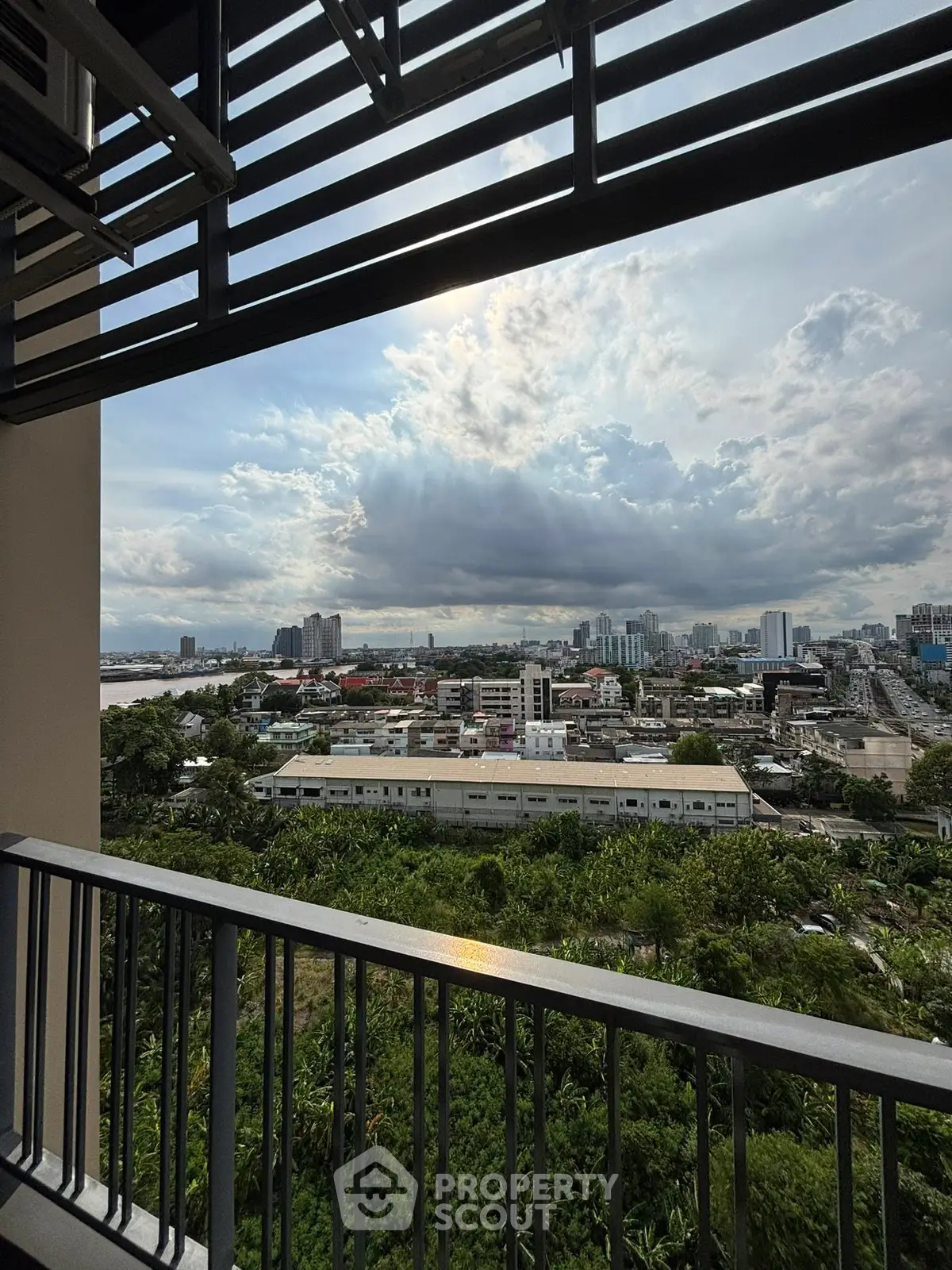 Stunning cityscape view from a high-rise balcony with expansive skyline and lush greenery.
