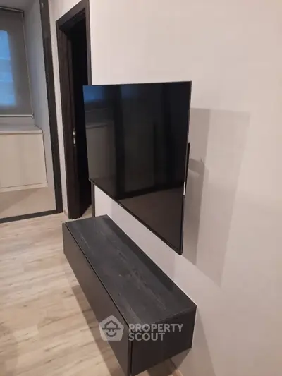 Modern living room with wall-mounted TV and sleek storage unit.