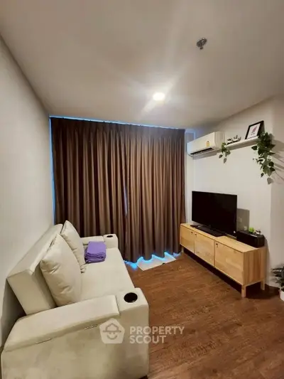 Cozy living room with modern sofa, TV, and air conditioning.