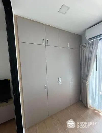 Modern bedroom with built-in wardrobe and air conditioning unit