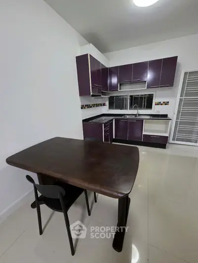 Modern kitchen with sleek purple cabinets and dining table, perfect for contemporary living.