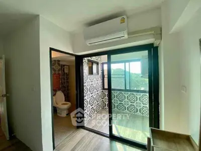 Modern apartment with balcony and bathroom, featuring stylish tile design and air conditioning.