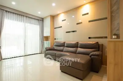 Spacious modern living room with elegant leather sofa and large window.