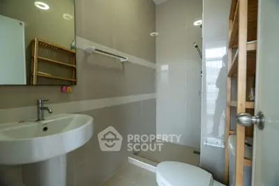 Modern bathroom with sleek fixtures and neutral tones, featuring a pedestal sink and walk-in shower.