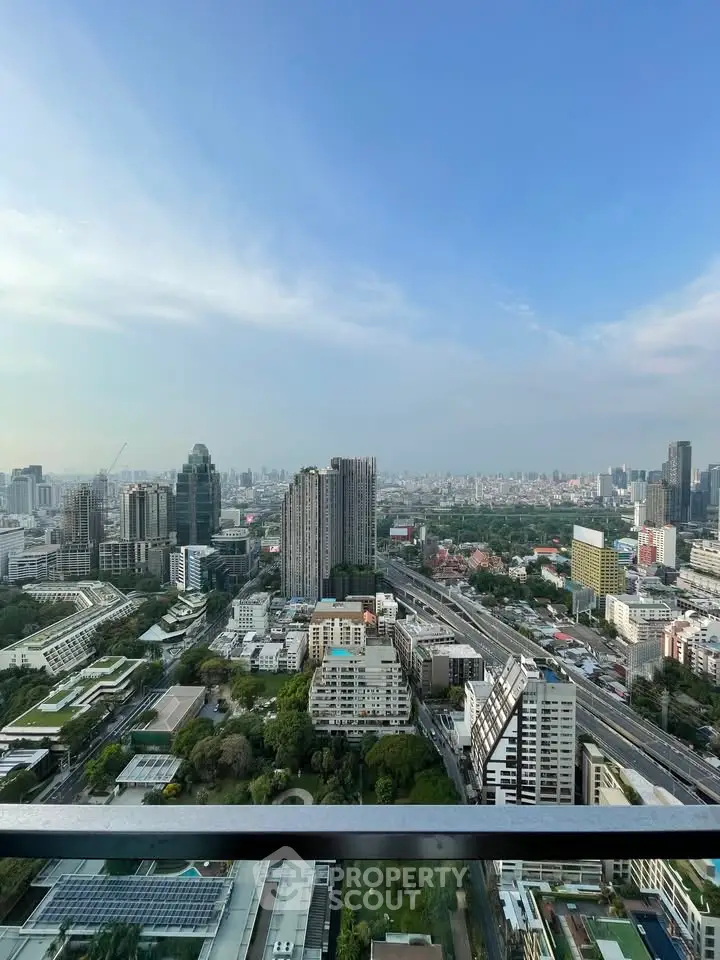 Stunning cityscape view from high-rise balcony with expansive skyline and lush greenery.