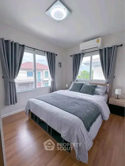 Cozy bedroom with modern decor, featuring large windows and stylish curtains, perfect for relaxation.