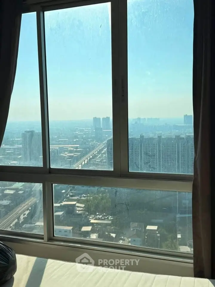 Stunning high-rise city view from a modern apartment window, showcasing urban skyline and bright skies.