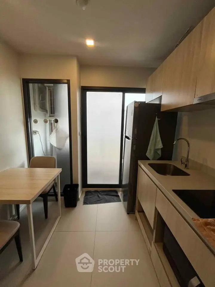 Modern kitchen with sleek cabinetry and dining area in a cozy apartment setting.