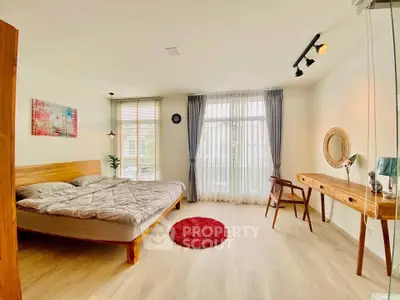 Spacious bedroom with modern decor and natural light, featuring a cozy bed and stylish desk.