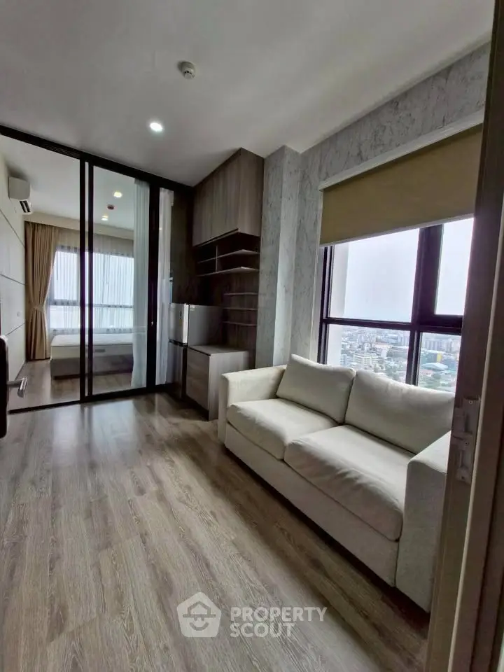 Modern apartment living room with city view, featuring sleek wooden flooring and cozy white sofa.