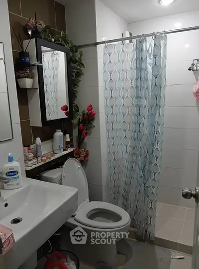 Charming bathroom with modern fixtures and stylish decor, featuring a shower curtain and ample storage space.