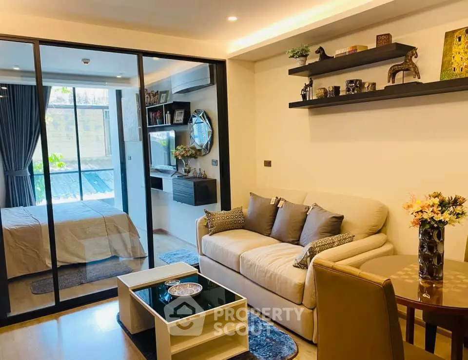 Modern living room with cozy sofa and stylish decor adjacent to a bedroom with glass partition.
