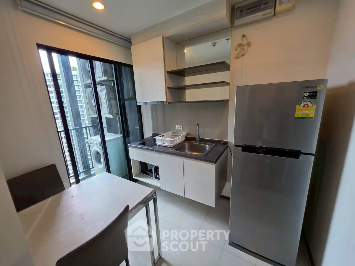 Modern compact kitchen with stainless steel fridge and balcony view