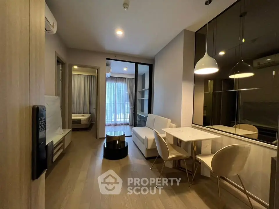Modern apartment interior with open living and dining area, featuring stylish furniture and large windows.