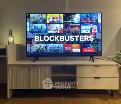 Modern living room with sleek TV stand and large flat-screen TV displaying streaming service.