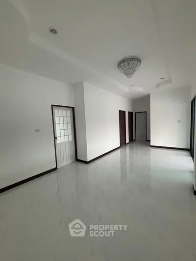 Spacious and elegant hallway with modern chandelier and sleek flooring