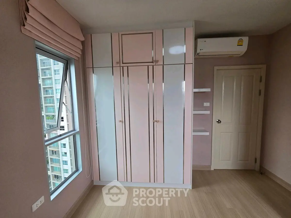 Chic bedroom with modern wardrobe and air conditioning in a high-rise apartment with city view.