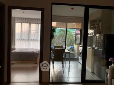 Modern apartment with open kitchen and cozy bedroom, featuring a balcony with lush greenery view.