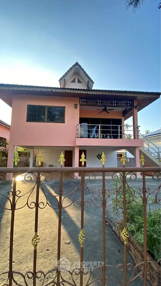 Charming two-story house with balcony and gated driveway, perfect for family living.