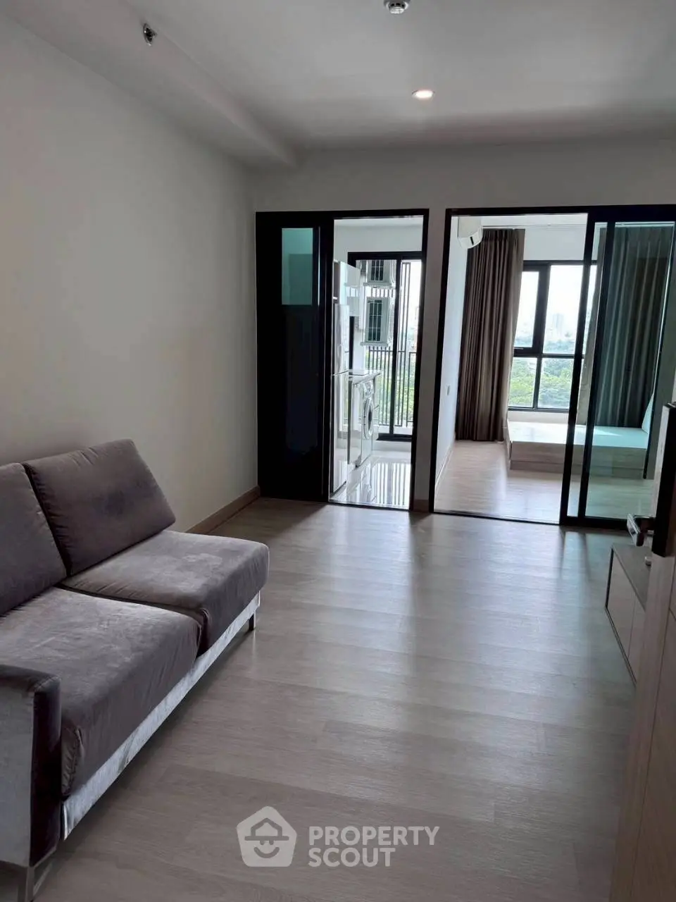 Modern apartment interior with sleek design, featuring a cozy living area and a view into a bright bedroom.