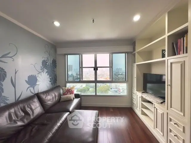 Stylish living room with large window and built-in shelving, featuring a cozy leather sofa and city view.