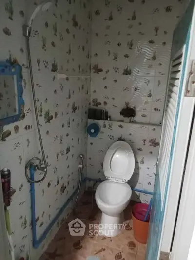 Compact bathroom with shower and toilet, featuring ocean-themed tiles.