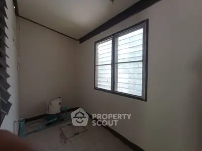 Small empty room with window and air conditioning unit, ideal for storage or utility use.