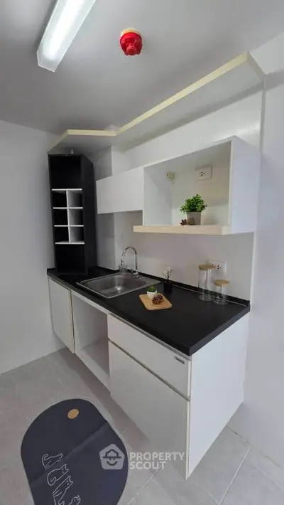 Modern minimalist kitchen with sleek black countertops and open shelving, perfect for compact living spaces.