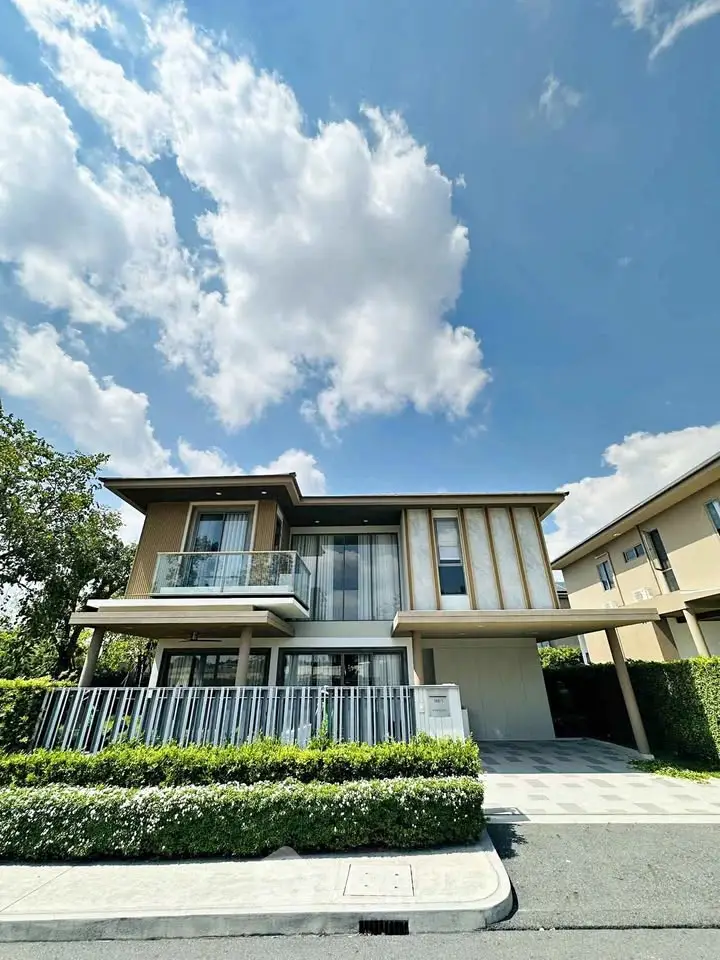 Modern two-story house with large windows and balcony under a clear blue sky.