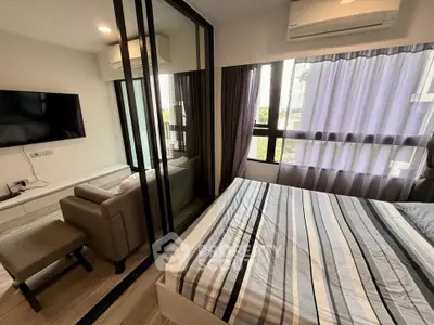 Modern bedroom with glass partition, striped bedding, and wall-mounted TV in stylish apartment.