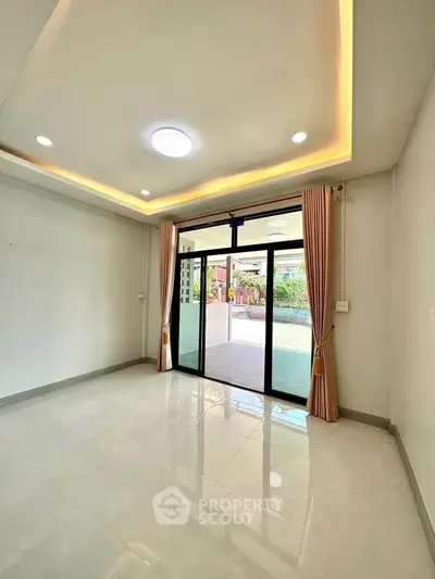 Spacious living room with modern lighting and large sliding glass doors leading to a patio.