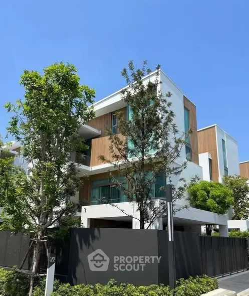 Modern three-story house with sleek design and lush greenery