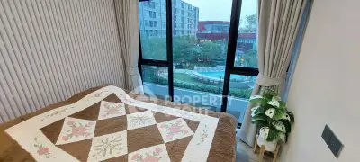 Cozy bedroom with large window offering a stunning view of the pool and garden area.