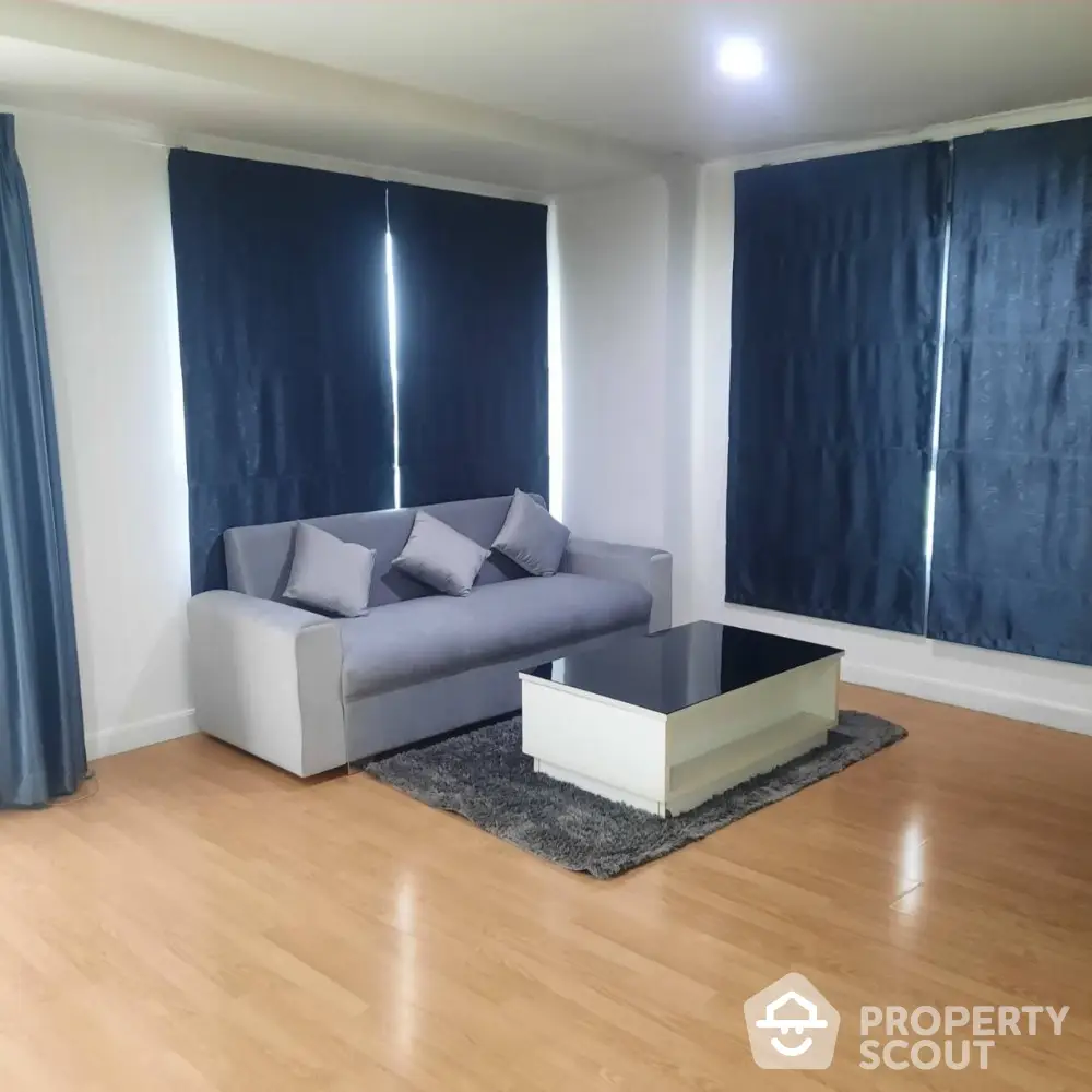 Modern living room with stylish gray sofa and sleek coffee table on wooden flooring.