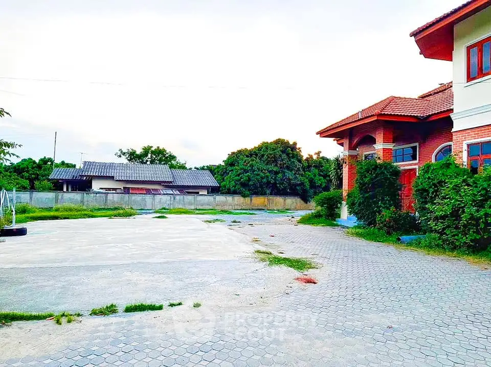 Spacious property with paved driveway and lush greenery, perfect for serene living.