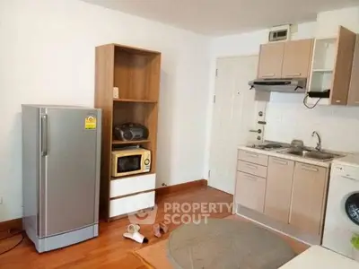 Cozy kitchen with modern appliances and wooden flooring in a compact apartment.